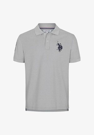 Grijs kortärmlig poloshirt met een geborduurd embleem op de linkerborst, gecombineerd met een blauwe spijkerbroek en witte sneakers.