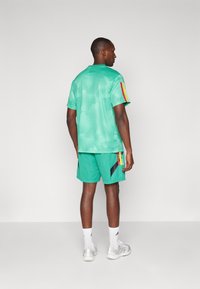 Green athletic jersey and shorts featuring a subtle pattern, with multi-colored stripes on the sleeves and black accents on the shorts.