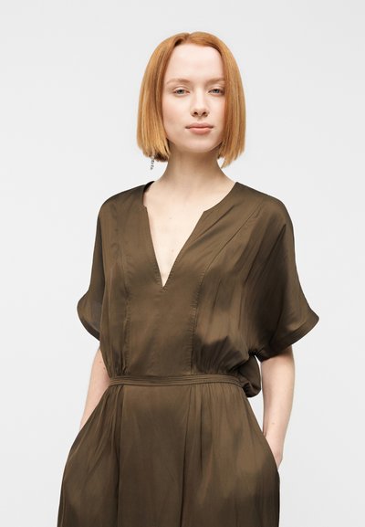 Φόρεμα κοντομάνικο, ελιάς, σε ελαφρύ ύφασμα με V-λαιμόκοψη και σούρες στη μέση. Διαθέτει πλαϊνές τσέπες και απαλό, ρέον ύφασμα.