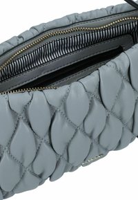 Borsa a mano in pelle grigia con design trapuntato e accenti a forma di petalo. L'interno presenta una fodera a strisce e scomparti con zip a contrasto.