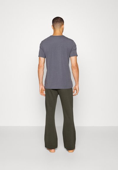 T-shirt cinza de algodão com mangas curtas, combinado com calças evasê verde-oliva. O tecido parece suave, com uma textura lisa e poucos detalhes.
