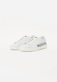 Bijele kožne tenisice s gumenim potplatima, s crnim "VALENTINO" logotipom sa strane, s vezicom i dizajnom zaobljenog vrha.