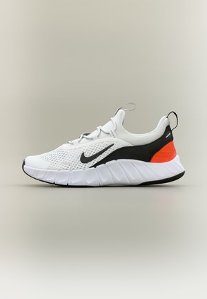 Baskets Nike blanches et noires avec dessus en maille, semelle blanche épaisse, logo Swoosh noir et accent orange au talon, vues de profil.