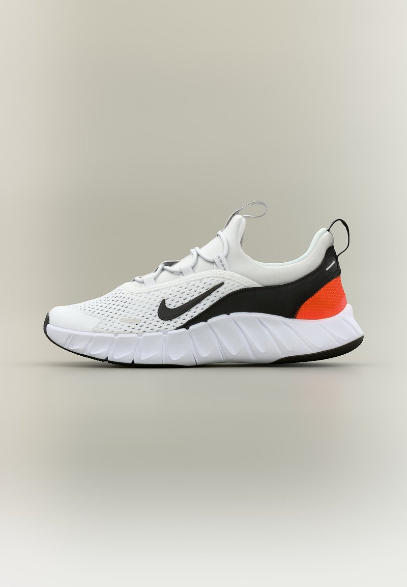 Baskets Nike blanches et noires avec dessus en maille, semelle blanche épaisse, logo Swoosh noir et accent orange au talon, vues de profil.