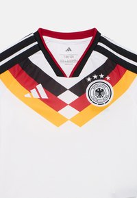 Camisola de futebol branca com riscas diagonais em vermelho, preto e amarelo, design em V, ombros com três riscas pretas e logótipo bordado.