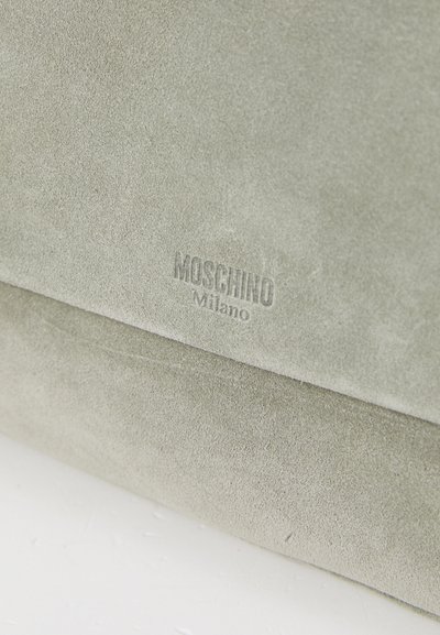Grön mocka-handväska med präglad "Moschino Milano"-logotyp, slät yta och minimalistisk design med en strukturerad form.