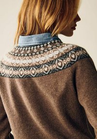 Ruskea pusero, jossa valkoista, mustaa ja ruskeaa kuviollista kantaa. Alla näkyy farkkukankaasta tehty kaulus, joka korostaa tekstuuria ja muotoilua.