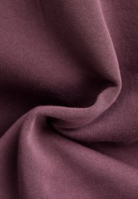 Ljubičasta tkanina s mekim teksturom, glatkom površinom i finim pletenjem. Materijal se elegantno pada, ističući suptilnu dubinu boje i detalje.