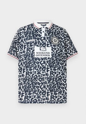 Polo avec imprimé abstrait noir et blanc, col blanc avec rayures rouges, texte « Weekend Offender » et logos sur la poitrine et les manches.