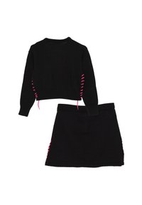 Maglione nero a maglia con lacci rosa sui lati abbinato a una gonna nera con lacci rosa coordinati, texture liscia e design cropped.