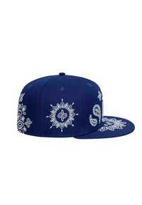 Cappellino snapback blu con motivi ricamati bianchi che raffigurano disegni floreali e paisley sui lati e sulla visiera, realizzato in tessuto strutturato.