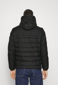 Czarna, ocieplana kurtka z kapturem, z poziomymi przeszyciami pikowanymi i elastycznymi mankietami. Widok od tyłu ukazuje gładką fakturę i prosty design.