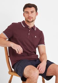 Maroon polo shirt with white collar and sleeve accents, featuring a two-button placket and logo embroidery, worn with navy cargo shorts.