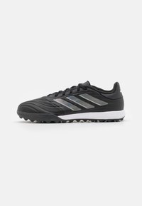 Scarpe da calcio nere con tomaia sintetica testurizzata, tre strisce riflettenti argento e una suola intermedia bianca. Presentano una suola in gomma modellata per una migliore trazione.