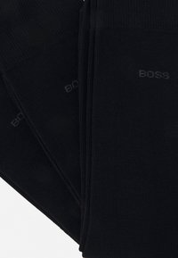 Schwarze Baumwollsocken mit Rippendesign, auf der Seite in Grau mit dem Markennamen "BOSS" bedruckt. Standard Crew-Länge.