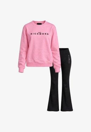 Felpa rosa con scollo a girocollo con la scritta "John Richmond" e pantaloni neri a zampa con la scritta "Richmond" sul lato.
