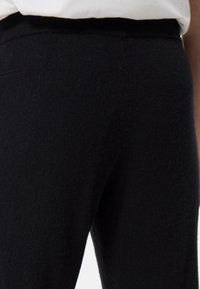 Schwarze Wollhosen mit einer weichen, strukturierten Oberfläche, ausgestattet mit einem elastischen Bund und einem taillierten Schnitt für Komfort und Stil.