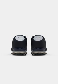 Tengerészi sportcipők sima textil felsőrészsel, szürke sarokpánttal és mintás talppal ellátott gumitalppal. Minimalista dizájn.