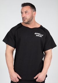 Zwart shirt met korte mouwen, gemaakt van textuurstof, met een losse pasvorm en het "GORILLA WEAR" logo in het wit op de voorkant.