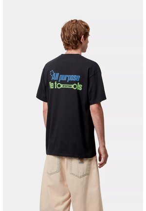 Camiseta de algodón negra con texto azul y verde en la parte posterior que dice "Propósito general" y "herramientas" con un gráfico de una llave inglesa.