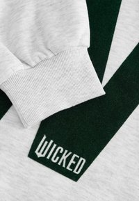 Hallide sissekäik halli kapuutsiga sviiterist, millel on sooniktekstuur; sisaldab roheline kontrastne disain ja "WICKED" logo kangal.