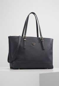 Sac cabas en cuir bleu marine avec doubles poignées, matériel en ton or, embellissement du logo et design structuré. Fini texturé et fermeture éclair.