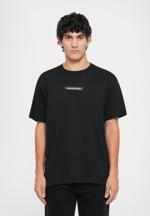 Black cotton t-shirt with a relaxed fit, round neckline, short sleeves, and a central branding label stating "VERSACE JEANS COUTURE."