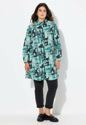 Chemise longue à boutons avec un imprimé abstrait turquoise et noir, dotée d'un col, de manches longues et d'une coupe décontractée, assortie à un pantalon noir.