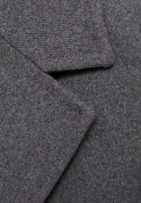 Gray wool fabric with a soft texture, featuring two overlapping lapels and a subtle woven pattern. Visible stitching detail along edges.