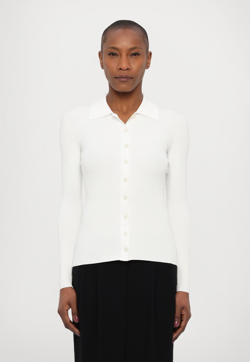 Witte ribgebreide lange mouwen cardigan met een kraag, voorzien van een knoopsluiting aan de voorkant en een getailleerd ontwerp. Glad textuur en lichte stof.