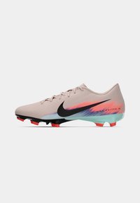 Chuteiras de futebol Nike com um cabedal rosa claro com um desenho em degradê azul e coral, logotipo preto e cravos multicoloridos na sola.
