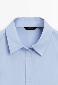 Light blue striped shirt featuring a classic collar, two white buttons, and a black label with brand name inside the collar.