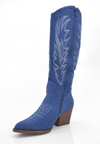 Botas de vaquero de denim azul con punta afilada, costuras decorativas en blanco, cremallera lateral y un tacón de madera apilado. Textura suave en toda la bota.