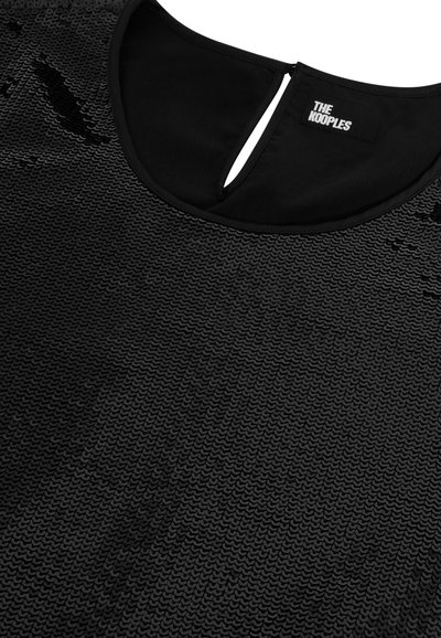 Top nero con paillettes e scollatura rotonda, apertura a chiave sulla schiena, dotato di un'etichetta che recita "THE KOOPLES."