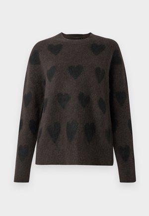 Brun genser med en myk tekstur, med et mønster av svarte hjerter. Den har rund hals og lange ermer.