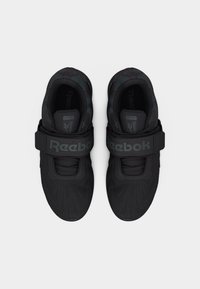 Μαύρα αθλητικά παπούτσια Reebok με δίχτυ υφής, φαρδιά λωρίδα βέλκρο με την ετικέτα "Reebok" και κορδόνια, από την άνω όψη σε λευκό φόντο.