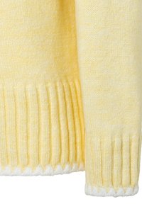 Yellow knitted sweater with ribbed cuffs and hem. Soft texture, light variations in color, and a white scalloped edge at the bottom.