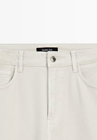 Pantaloni in cotone color crema con taglio dritto, dotati di una tasca frontale, chiusura con bottone in metallo e un etichetta nera del brand all'interno.