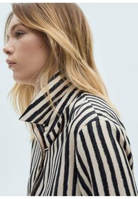 Gestreept overhemd met een hoge kraag, gekenmerkt door gedurfde zwarte strepen op een crèmekleurige achtergrond, gemaakt van een gladde stof. Knopdetails zichtbaar.