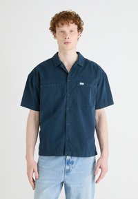 Navy blue short-sleeve shirt with a camp collar, two chest pockets, and button front detail. Made of lightweight fabric with a smooth texture.