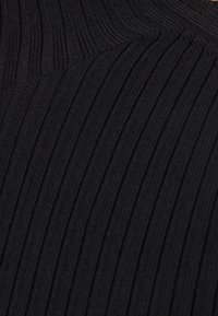 Gros plan d'un tissu tricoté côtelé noir avec un motif vertical et diagonal dans la texture.