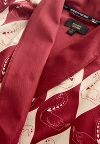 Punane ja kreemikatsega kimono, millel on luikede muster, tekstureeritud kangas, lai krae ja kontrastsed mustrid. Silt ütleb "ROCKETT & GEORGE."