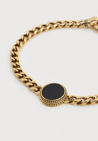 Βραχιόλι αλυσίδα από χρυσό με σχεδιασμό υφασμένων συνδέσμων και κεντρικό διακοσμητικό μαύρη στρογγυλή πέτρα με περιμετρικό κόσμημα από χάντρες.