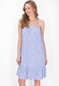 Rochie florală de un albastru deschis, cu bretele subțiri, tiv ondulat și modele florale albe pe un material moale și respirabil.
