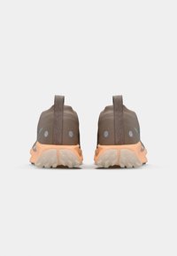 Brown trail running shoes with a breathable upper, orange outsole, textured detail, and reflective accents on the heel and sides.