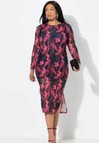 Vestido de manga larga con base negra y patrones florales en rosa, con un silueta ajustada y una abertura lateral, acompañado de un clutch negro.