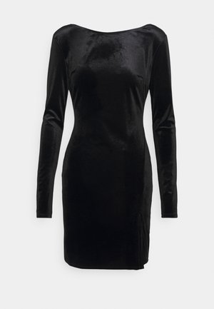 Robe noire en velours ajustée à manches longues, col bateau et ourlet longueur genoux, avec une fente latérale subtile.