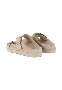 Beesedest nahkkingad, millel on laiad rihmad ja suured hõbedased pandlad, valgel taustal.