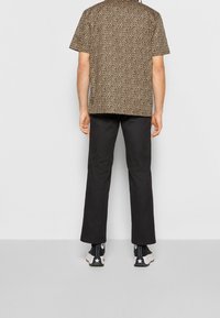 Koszula z krótkim rękawem w brązowym kolorze z czarnymi cętkami lamparcimi, w połączeniu z czarnymi spodniami. Obuwie to czarne botki za kostkę z białymi gwiazdkami.