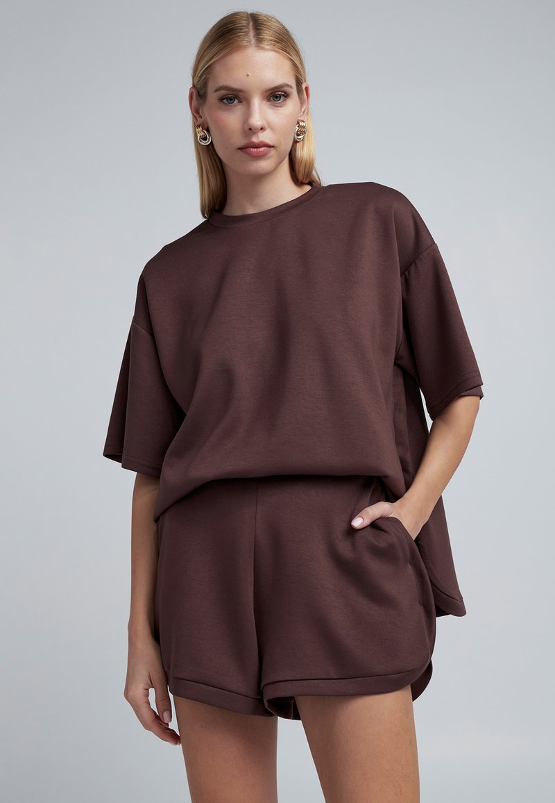 Brown cotton blend oversized T-shirt with short sleeves, paired with matching shorts featuring side pockets, smooth texture, and relaxed fit.